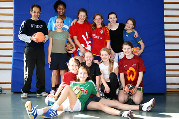 Hier sieht man ein Gruppenfoto der Schülerinnen der Handball-AG mit Herrn Faruk Aslan.